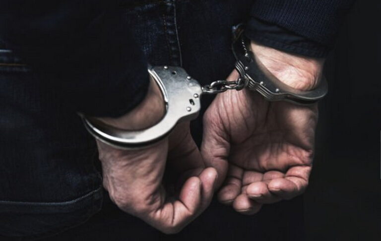 handcuffed arrested man behind prison bars. copy space